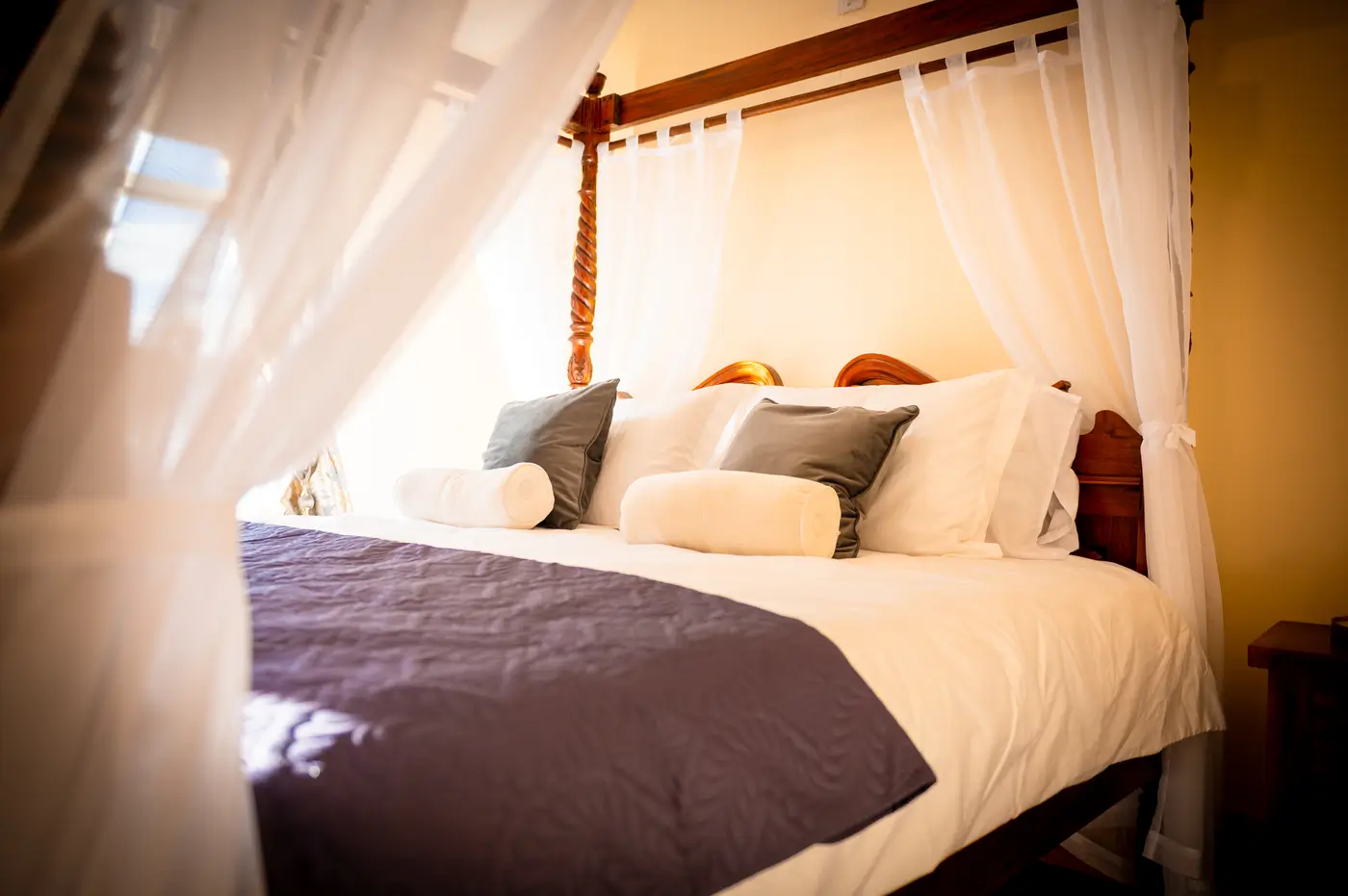 Four-poster wedding suite bed with luxurious pillows and purple bedding